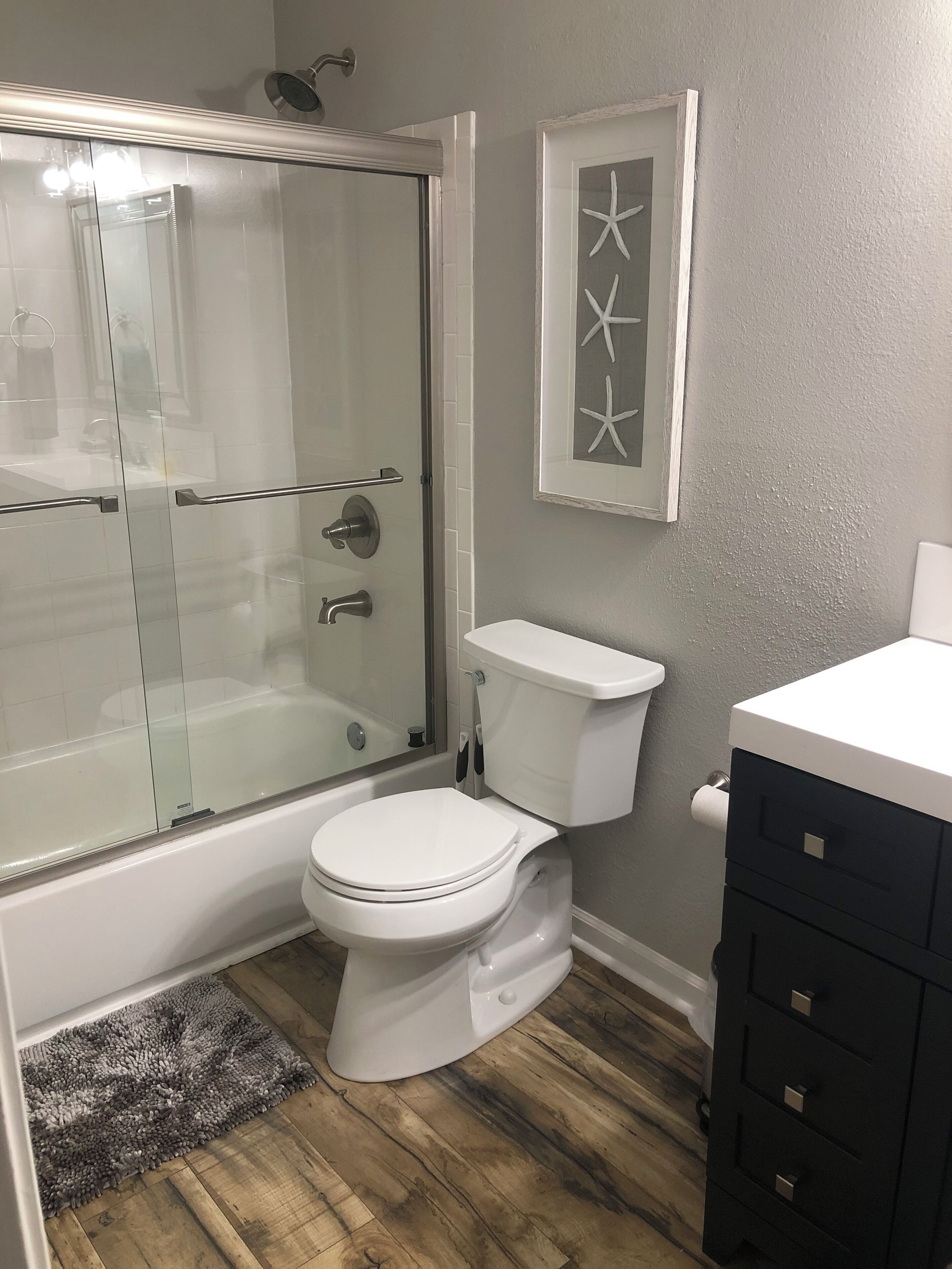 A bathroom with a glass-enclosed shower, a white toilet, and a black vanity.