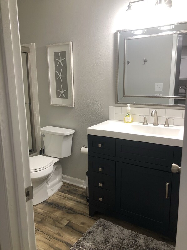 Une salle de bain comprenant des toilettes, un lavabo avec un miroir et un meuble de rangement.