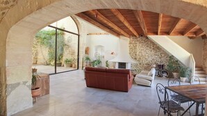 An interior with a stone wall, a wooden ceiling, a sofa, a table, and a fireplace. - The timeless (Saint-Dionisy)