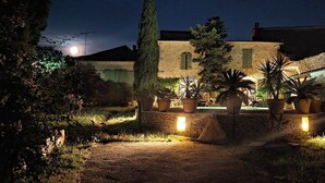 A stone building with a paved entrance, potted plants, and outdoor lighting. - The timeless (Saint-Dionisy)
