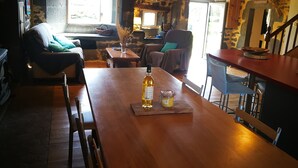 Een landelijk interieur met een houten eettafel, stoelen, een bank en een stenen muur.