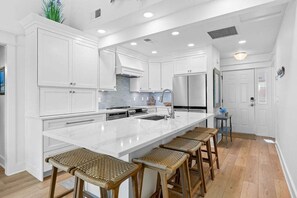 Una cocina moderna con armarios blancos, una isla grande y taburetes de bar.