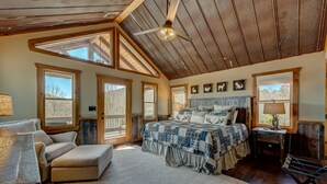 Une chambre spacieuse avec un grand lit, un plafond en bois et de nombreuses fenêtres.