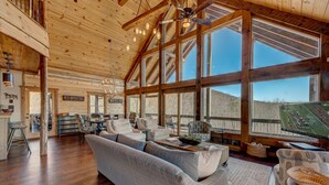 Un salon spacieux avec un grand canapé, un téléviseur et un plafond en bois.