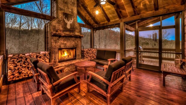 Un espace extérieur accueillant, doté d’une cheminée en pierre, de mobilier en bois et offrant une vue sur le paysage environnant.
