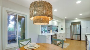 A modern kitchen with white cabinets, a stainless steel refrigerator, and a dining area with a wooden table and chairs. - Charming Lakefront Retreat in Palmetto Dunes! (Hilton Head Island)