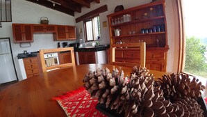 Een ruime keuken met houten kasten, een eettafel en uitzicht op groen.