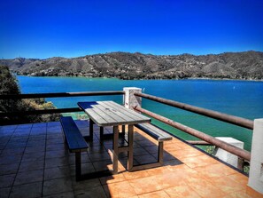 A terrace with a table and benches overlooking a lake with clear blue water and a hilly landscape in the background. - A completely private house overlooking the lake, offering unbeatable views   (La Peña)