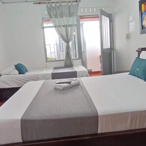 A hotel room with two beds, a window with curtains, a door, and a painting on the wall. - Hotel Villa Ángel (Neiva)
