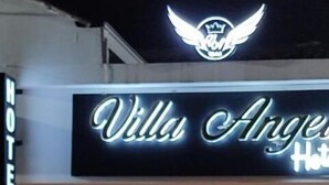 A hotel entrance with a neon sign reading "Villa Angeles Hotel" and a logo above it. - Hotel Villa Ángel (Neiva)