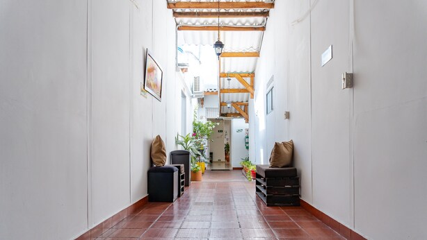 A hallway with a tiled floor, wooden beams, and potted plants. - Hotel Villa Ángel (Neiva)