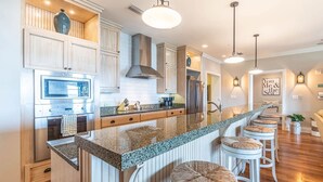 A modern kitchen with a central island, stainless steel appliances, and a bar area with stools.