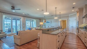 A spacious kitchen with a large island, wooden cabinets, and a dining area with a sofa and chairs.
