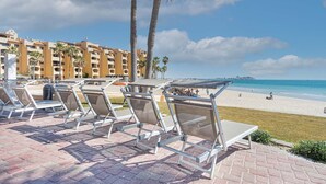 Un complexe hôtelier situé en bord de mer, doté de chaises longues et offrant une vue sur l’océan.