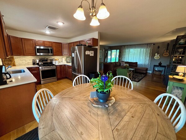 A modern kitchen with wooden cabinets, stainless steel appliances, and a dining area with a wooden table and chairs.