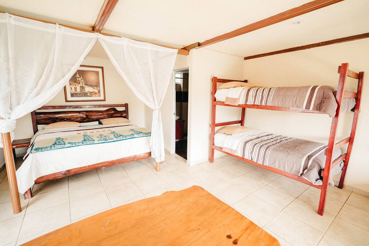 Ein Zimmer mit einem hölzernen Bett mit Baldachin, einem Etagenbett und Holzboden.