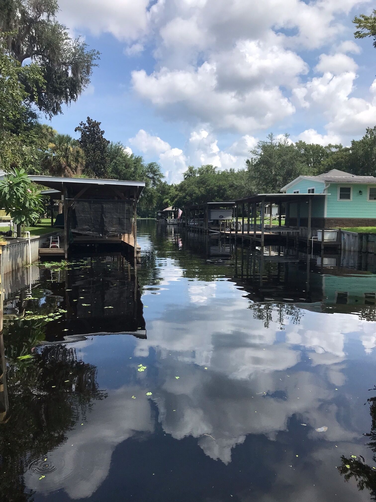 A calm waterway with wooden docks and houses on either side.