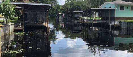 A calm waterway with wooden docks and houses on either side.