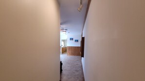 A narrow hallway with a tiled floor leading to a reception area with a wooden counter and a painting on the wall. - Tesla's lake Escape (Onalaska)