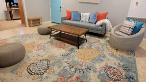 Un salon avec un canapé, une table basse et un tapis à motifs.