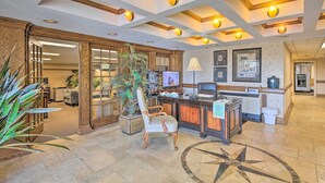 Un hall con mostrador de recepción, una planta grande, una silla estampada y un diseño decorativo en el piso.