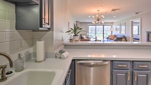 Una cocina moderna con un lavamanos de acero inoxidable, un horno empotrado y una encimera con dispensador de toallas de papel y jabón.