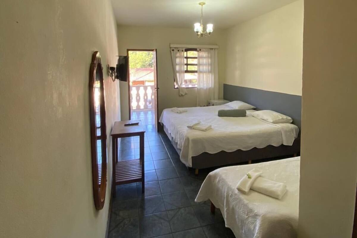 A narrow hallway with two beds, a desk, and a mirror.