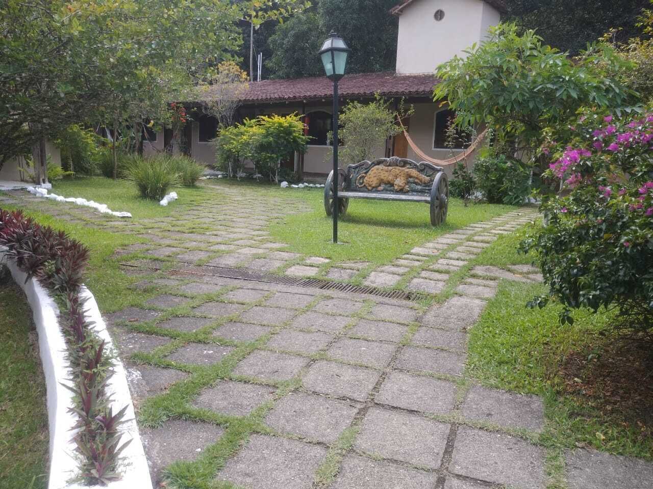 Un chemin de jardin pavé qui mène à un bâtiment doté d’un toit recouvert de tuiles.