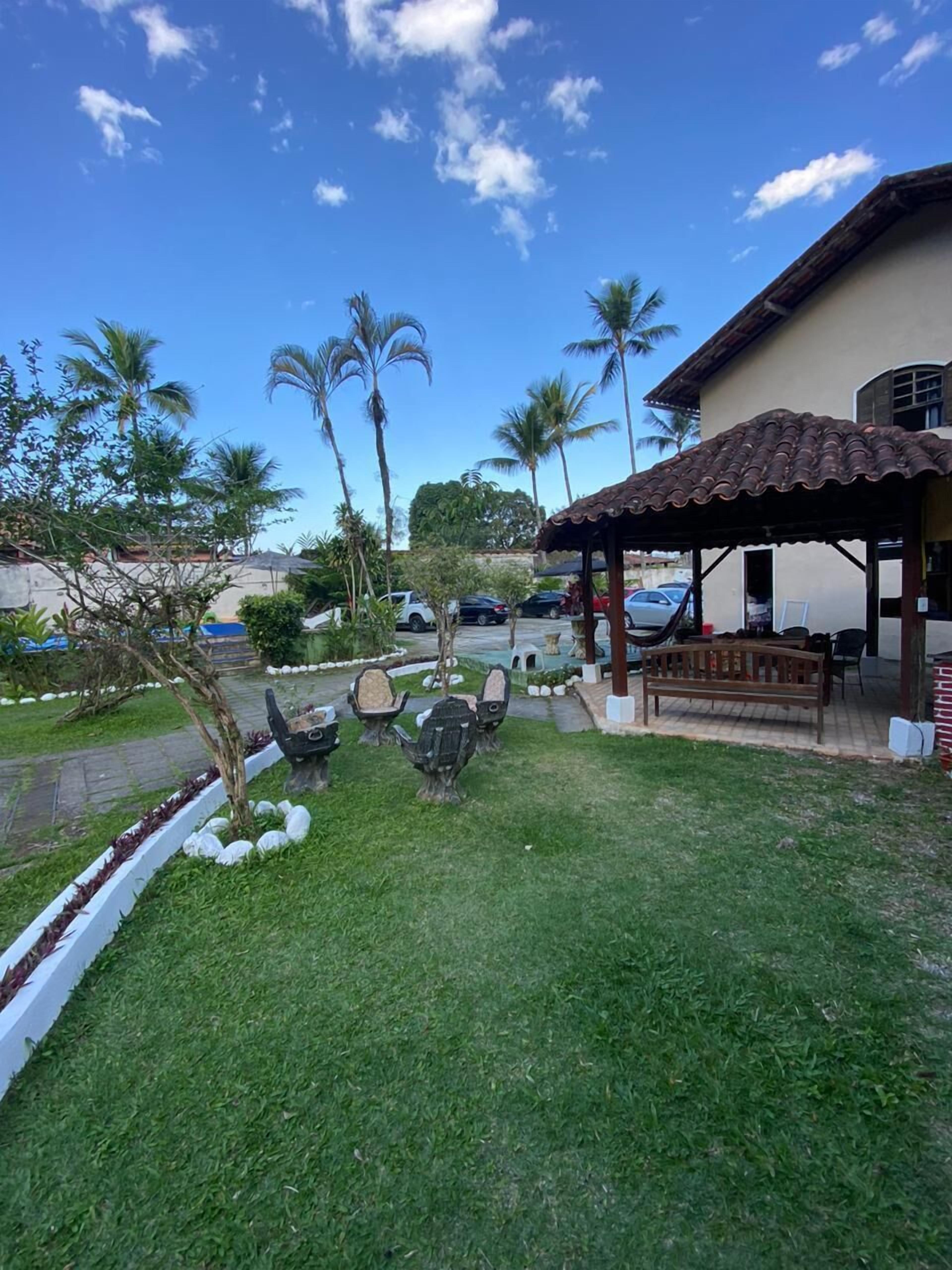 Un espace patio avec des sièges d’extérieur, des palmiers et un bâtiment doté d’un toit en tuiles.