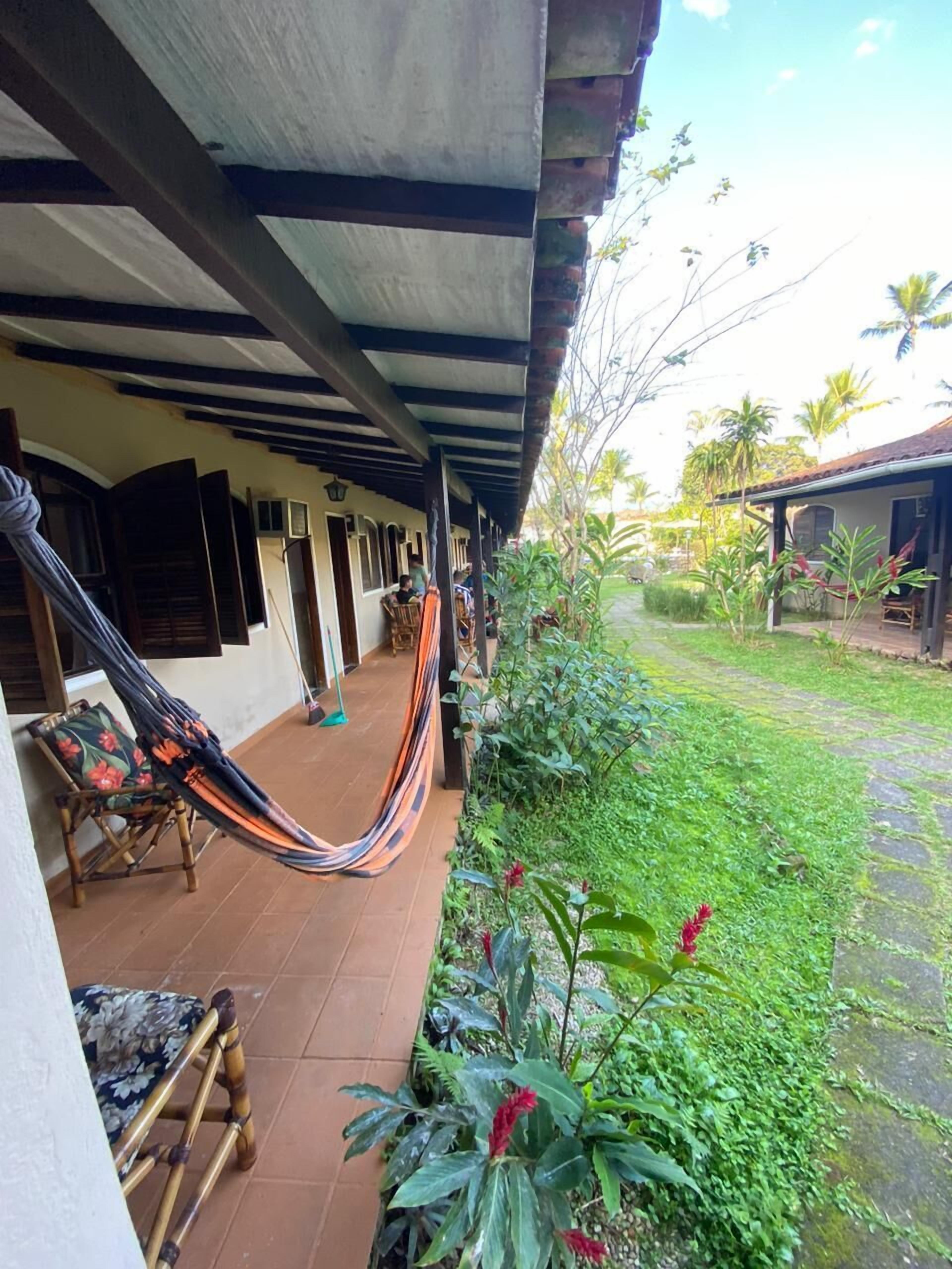 A covered porch with a hammock, a chair, and a small table.