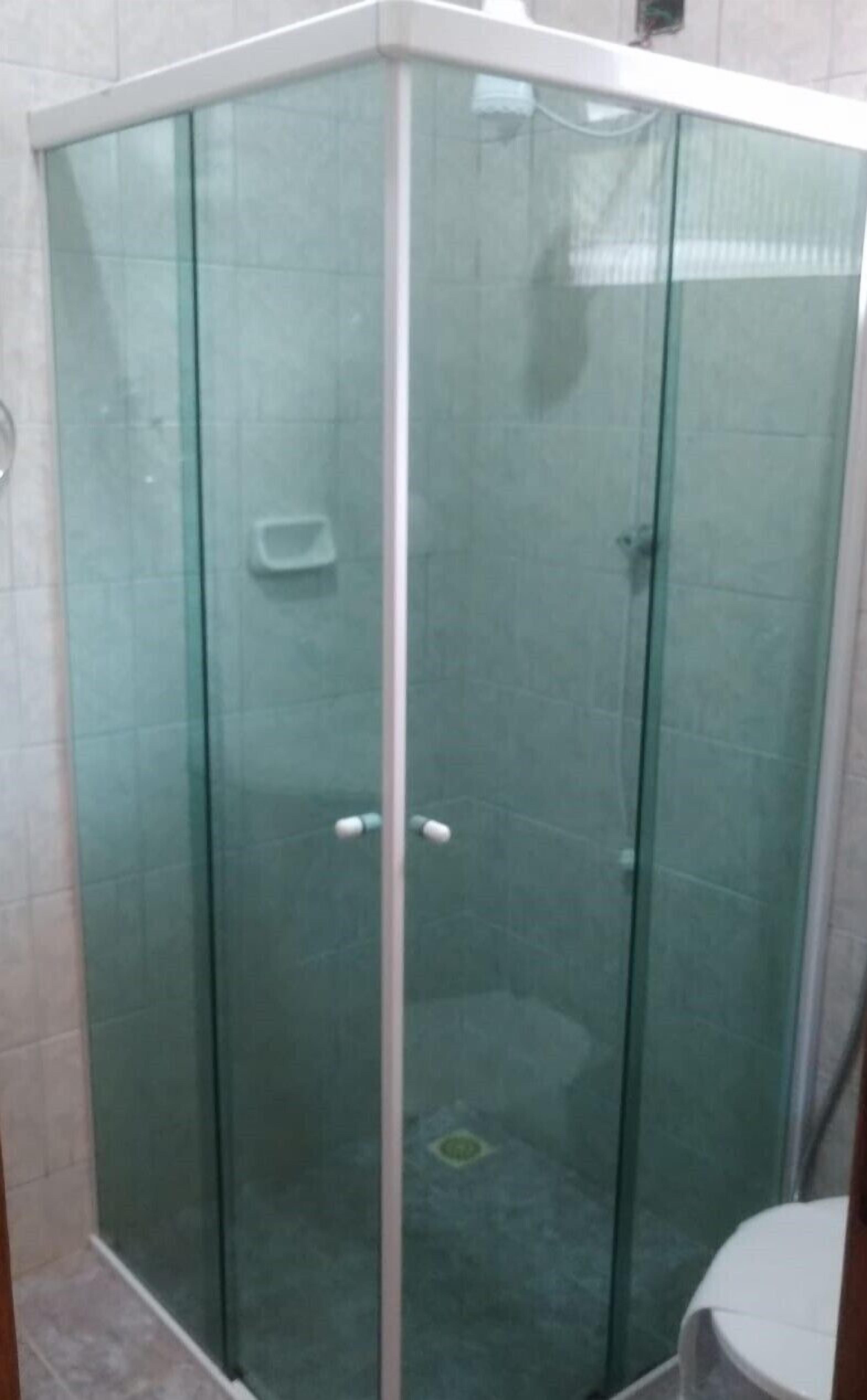 A glass-enclosed shower stall with a white base and a tiled wall.