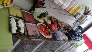 A buffet table with various food items and condiments. - Pousada Thamalu 228 (Paraty)