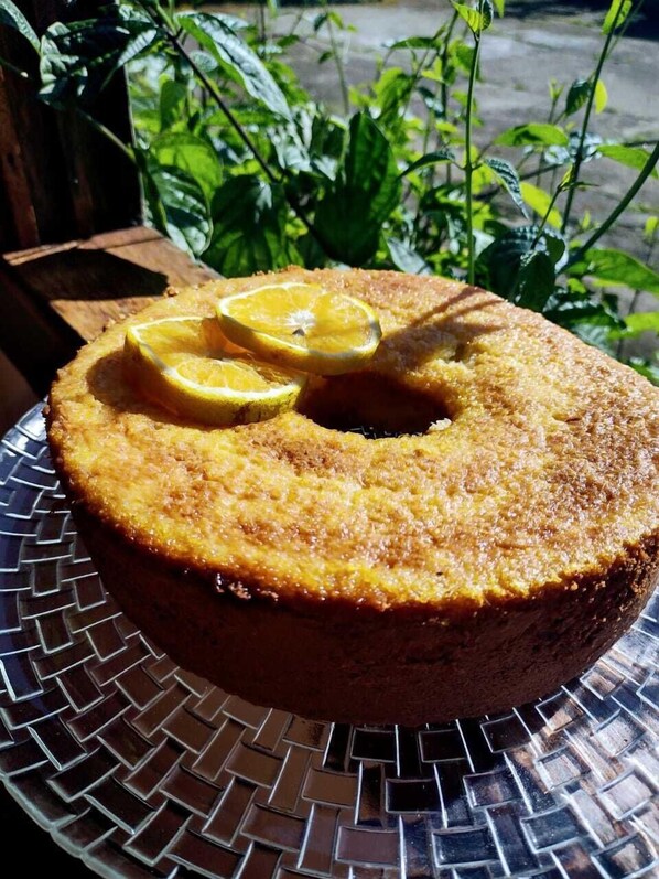 A round cake with lemon slices on top, placed on a metal plate.