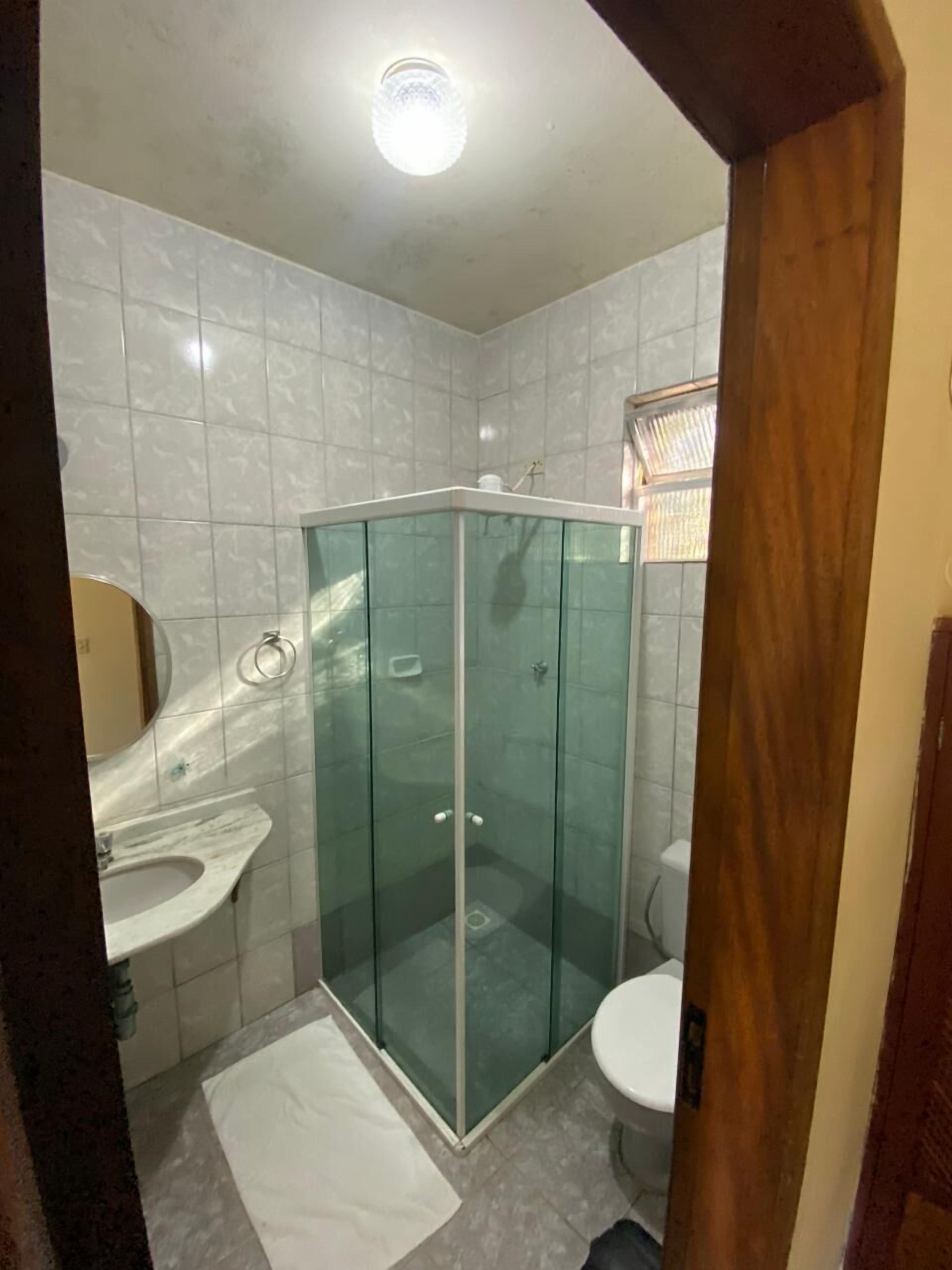 A bathroom with a glass-enclosed shower, a white sink, and a toilet.