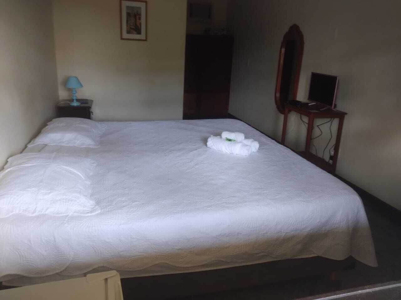 A neatly made bed with white linens and a towel on the bed.