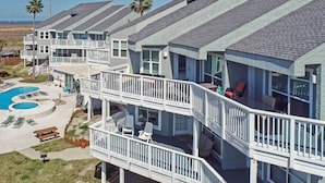 Um edifício residencial com várias andares, varandas, piscina e áreas de estar ao ar livre.