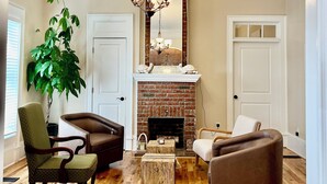 Un salon avec une cheminée, un plancher en bois et deux fauteuils.