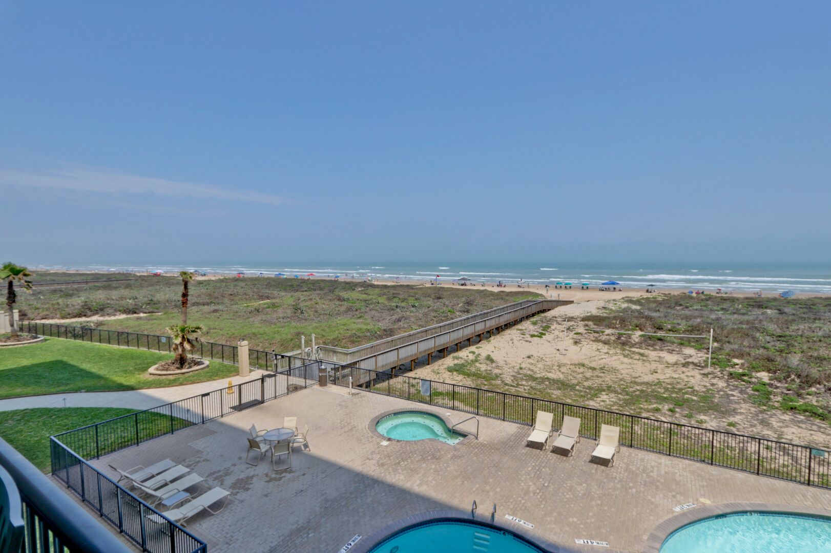 A pool area with two pools, a deck, and a beach view.