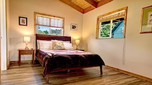 Un dormitorio con una cama de madera, dos mesitas de noche con lámparas y dos ventanas con persianas.