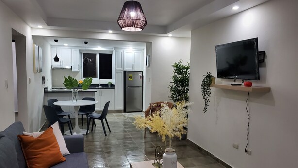 Una sala de estar moderna con un sofá, una mesa de centro y un televisor montado en la pared.