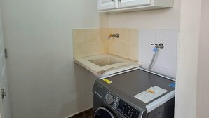 Un cuarto de lavado con lavadora, lavabo y armarios.