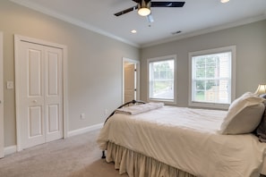 Cozy retreat with a bed, ceiling fan, and windows with blinds.