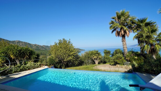 Una piscina azul cristalina con vistas al mar y a las montañas.
