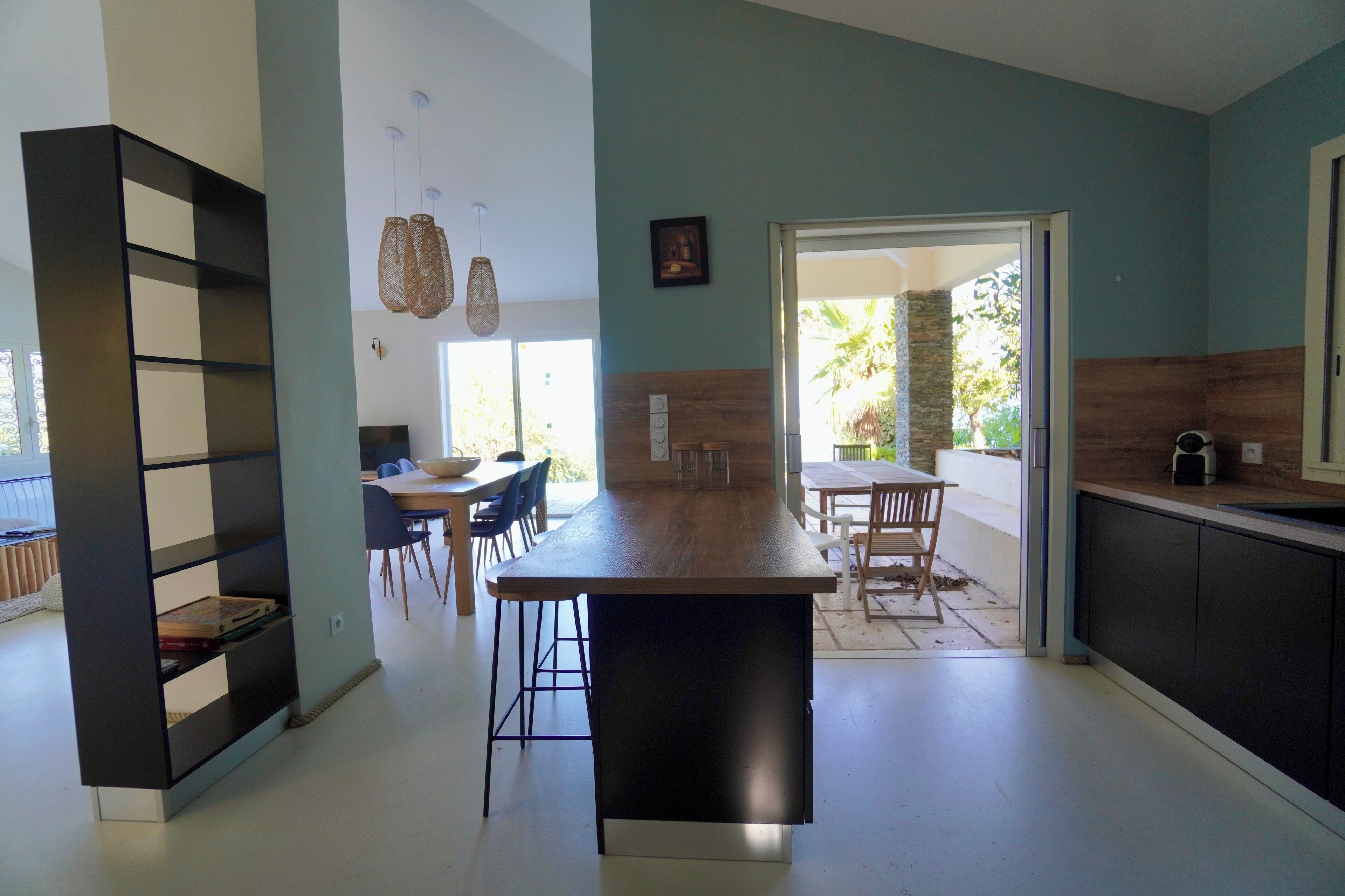 Une cuisine moderne dotée d’un îlot central, d’un coin repas avec des chaises et d’une bibliothèque.