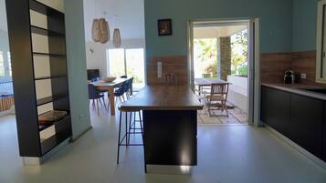 Une cuisine moderne dotée d’un îlot central, d’un coin repas avec des chaises et d’une bibliothèque.