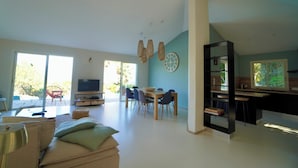 Amplia sala de estar con una mesa de comedor y sillas, televisor y área de cocina con barra.
