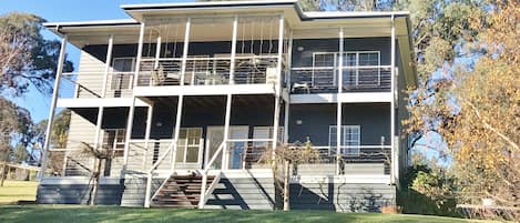 A two-story building with a balcony on the upper floor, a staircase leading to the entrance, and a well-maintained lawn in front.