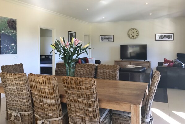 A living room with a dining area, a television, and a clock on the wall. - Hilltop Lane (Barwite)
