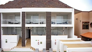 Un edifici modern de dues plantes amb teulada plana, grans finestres i una escala que mena a la planta superior.
