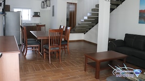 Un espai de vida modern amb zona de menjador, cuina i escala.
